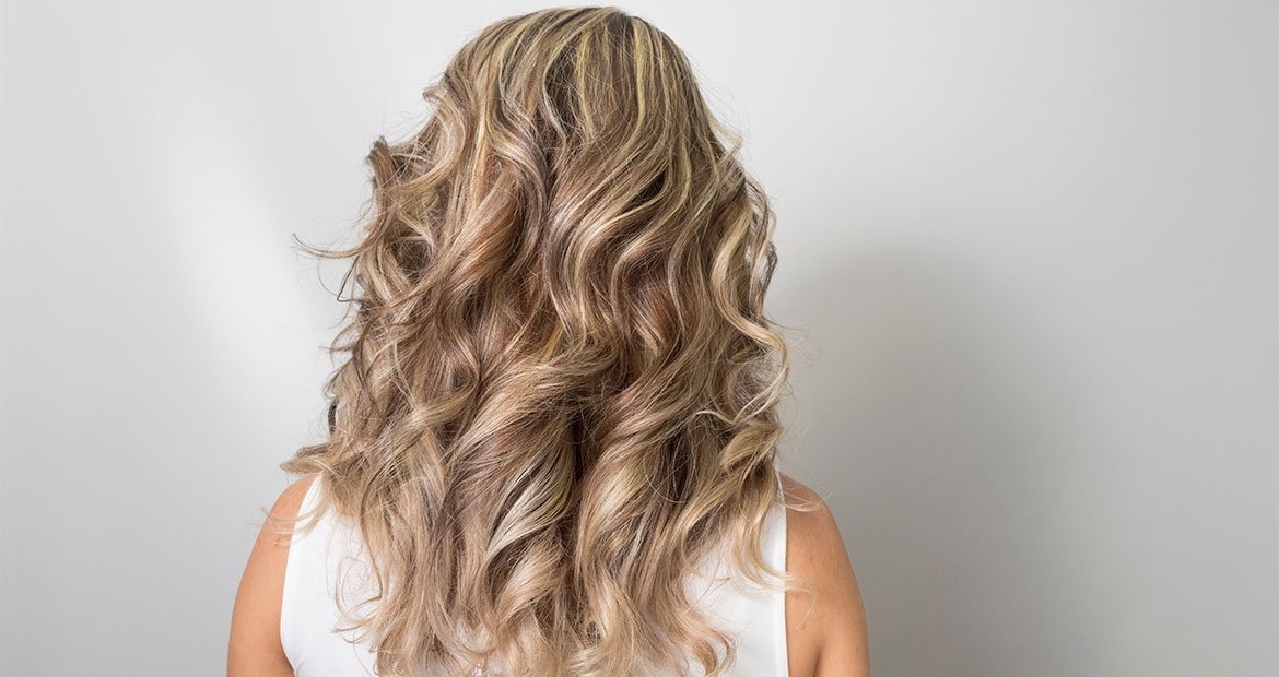 mulher branca posando para a foto de costas com cabelo com luzes na técnica highlights